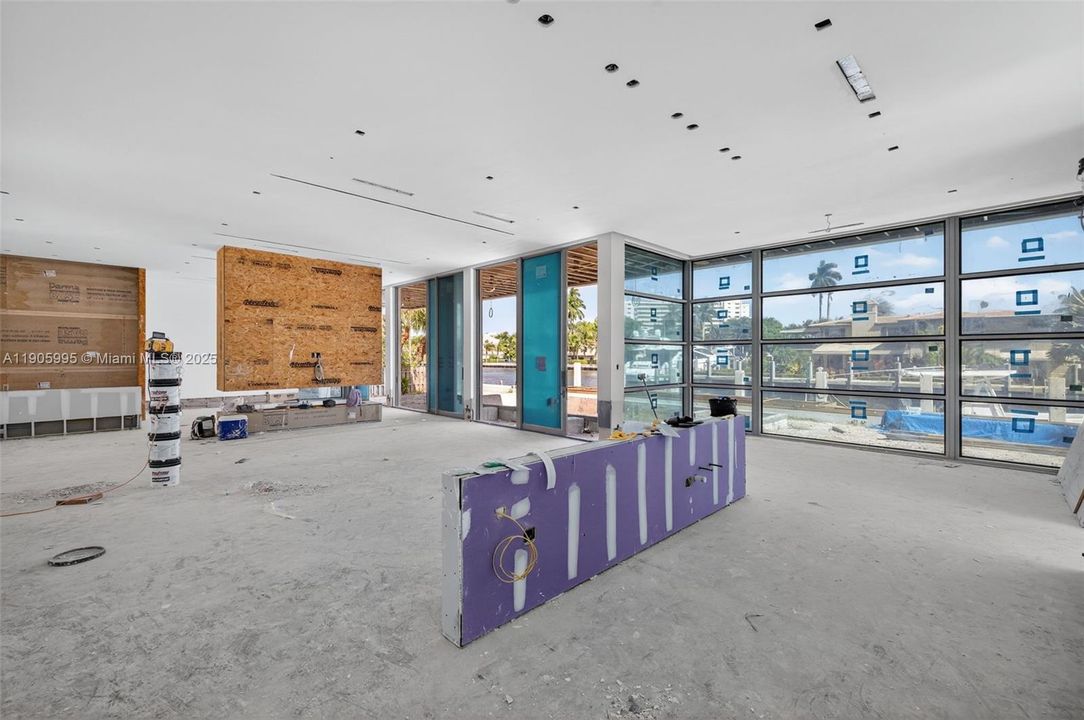 Actual photo as of Oct 31, 2025. Ceiling to have flush mounted architectural lighting. View from back of kitchen toward the dining area (with windows)