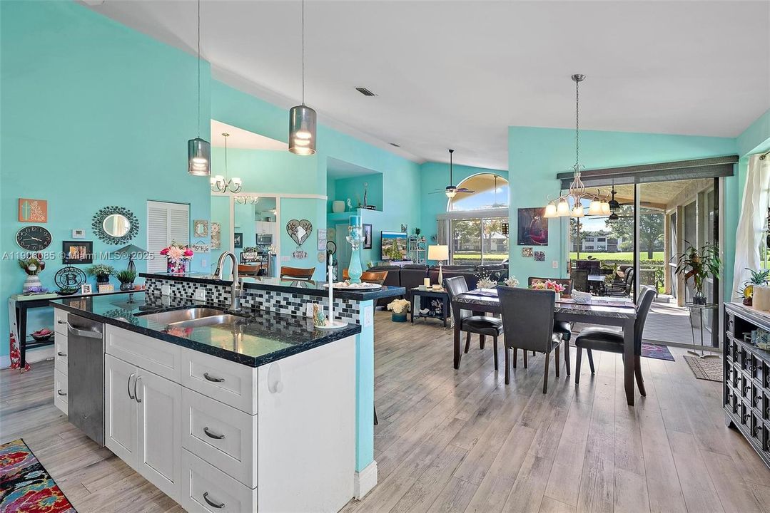 Remodeled Kitchen with granite counter tops and stainless-steel appliances. Opens to Dining area and Living room with vaulted ceilings. Slider Doors to outside patio and screened in porch.