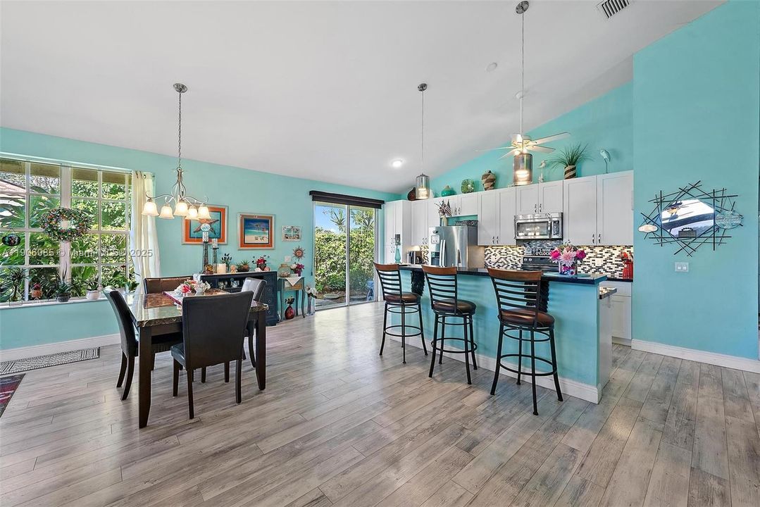 Remodeled Kitchen with granite counter tops and stainless-steel appliances. Opens to Dining area and Living room with vaulted ceilings. Slider Doors to outside patio and screened in porch.