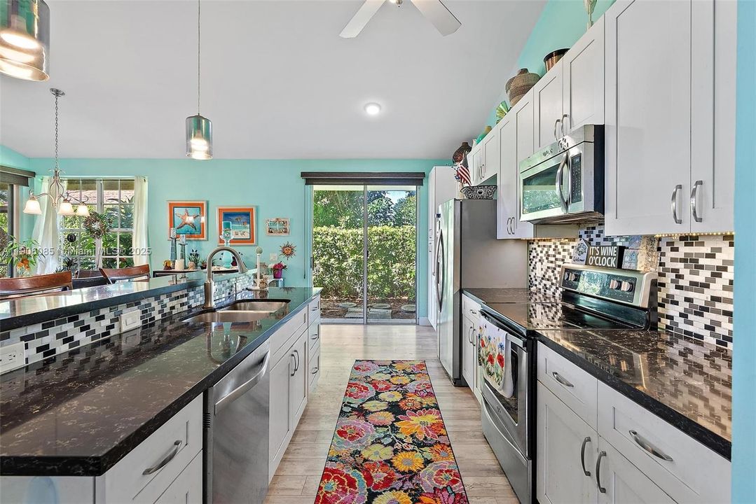 Remodeled Kitchen with granite counter tops and stainless-steel appliances. Opens to Dining area and Living room with vaulted ceilings. Slider Doors to outside patio and screened in porch.