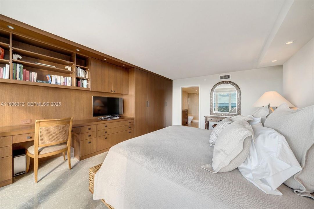Elegant primary bedroom with custom office desk.