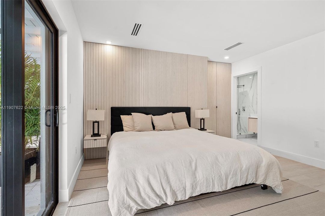 Custom wood paneling conceals a seamless entrance to the walk-in closet—elevating both the aesthetic and functionality of the primary suite.