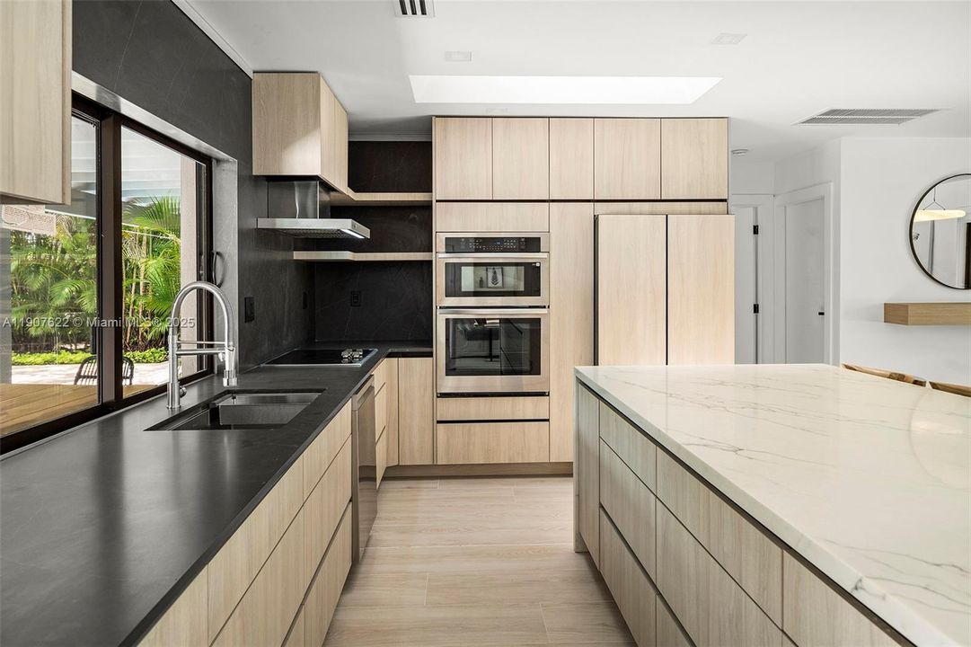 Top-of-the-line integrated appliances and full-height custom cabinetry create a clean, minimalist aesthetic with maximum functionality.