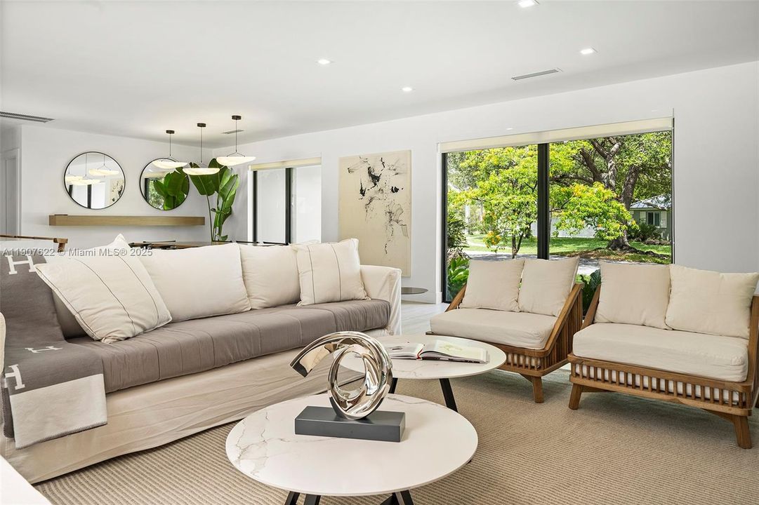 A bright and spacious living room surrounded by oversized windows that bring the outdoors in—flooded with natural light and tranquil garden views.