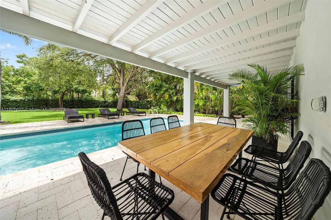 The 55-foot covered terrace offers the perfect outdoor dining and lounging space—framed by lush greenery and a sunlit pool for ultimate relaxation and entertaining.