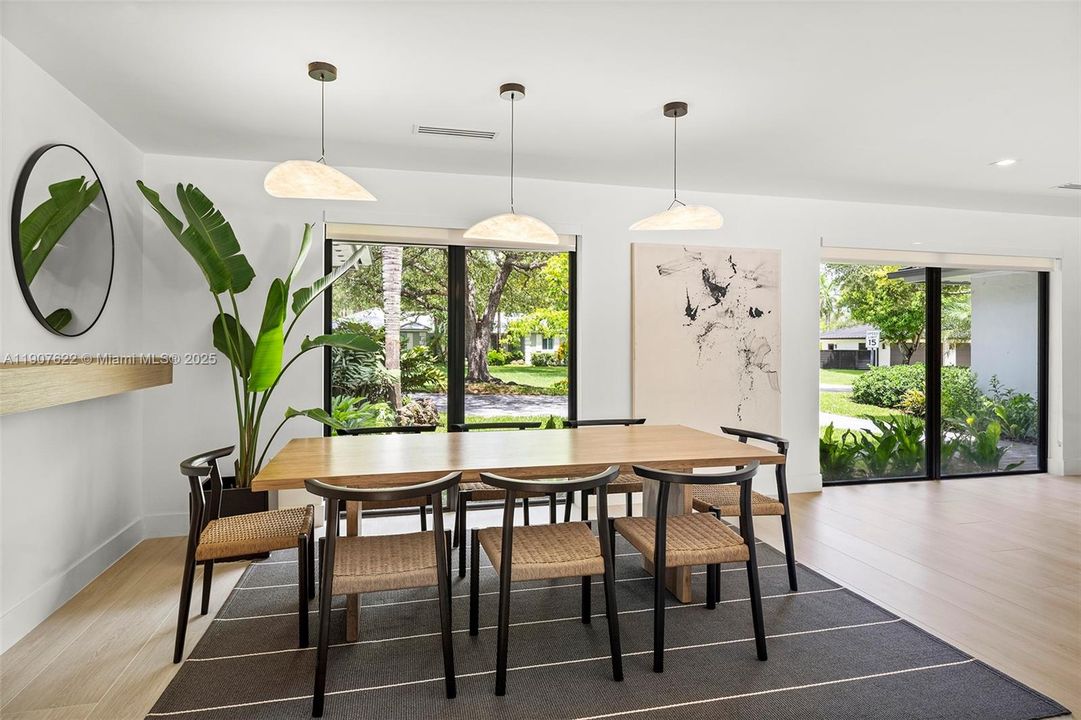 A bright dining area framed by large windows that bring in natural light and lush garden views—blending indoor comfort with outdoor beauty.