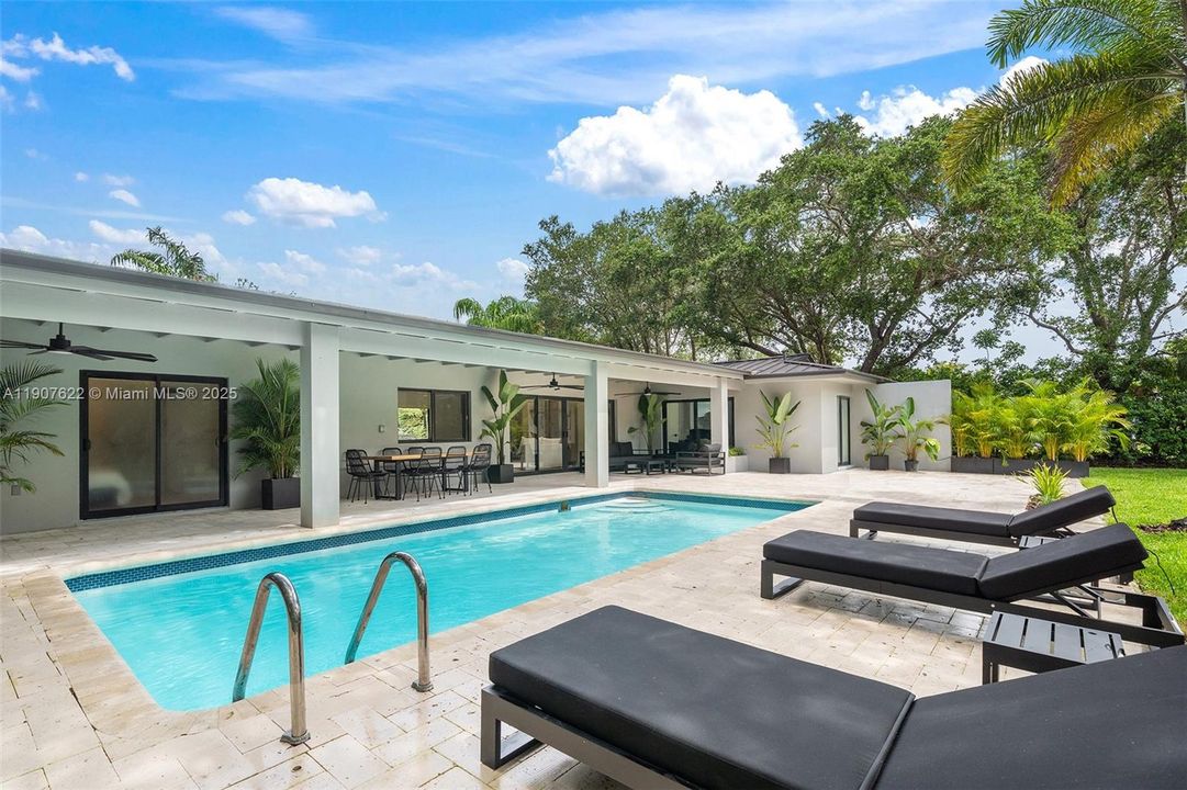 A resort-style backyard designed for relaxation and entertaining—lush landscaping, spacious pool deck, and a fully covered terrace complete the dream.