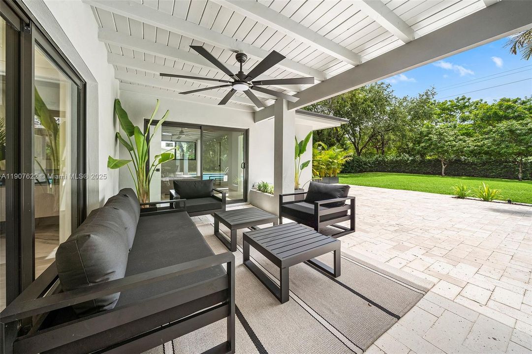 A true outdoor lounge under a modern covered patio—complete with ceiling fan and lush garden views for year-round enjoyment.