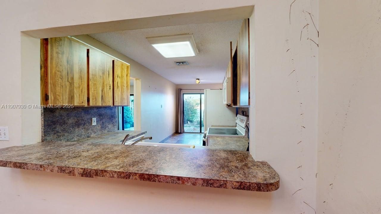 Functional and sunlit kitchen ready for your modern touch, with easy access to both dining and living areas.