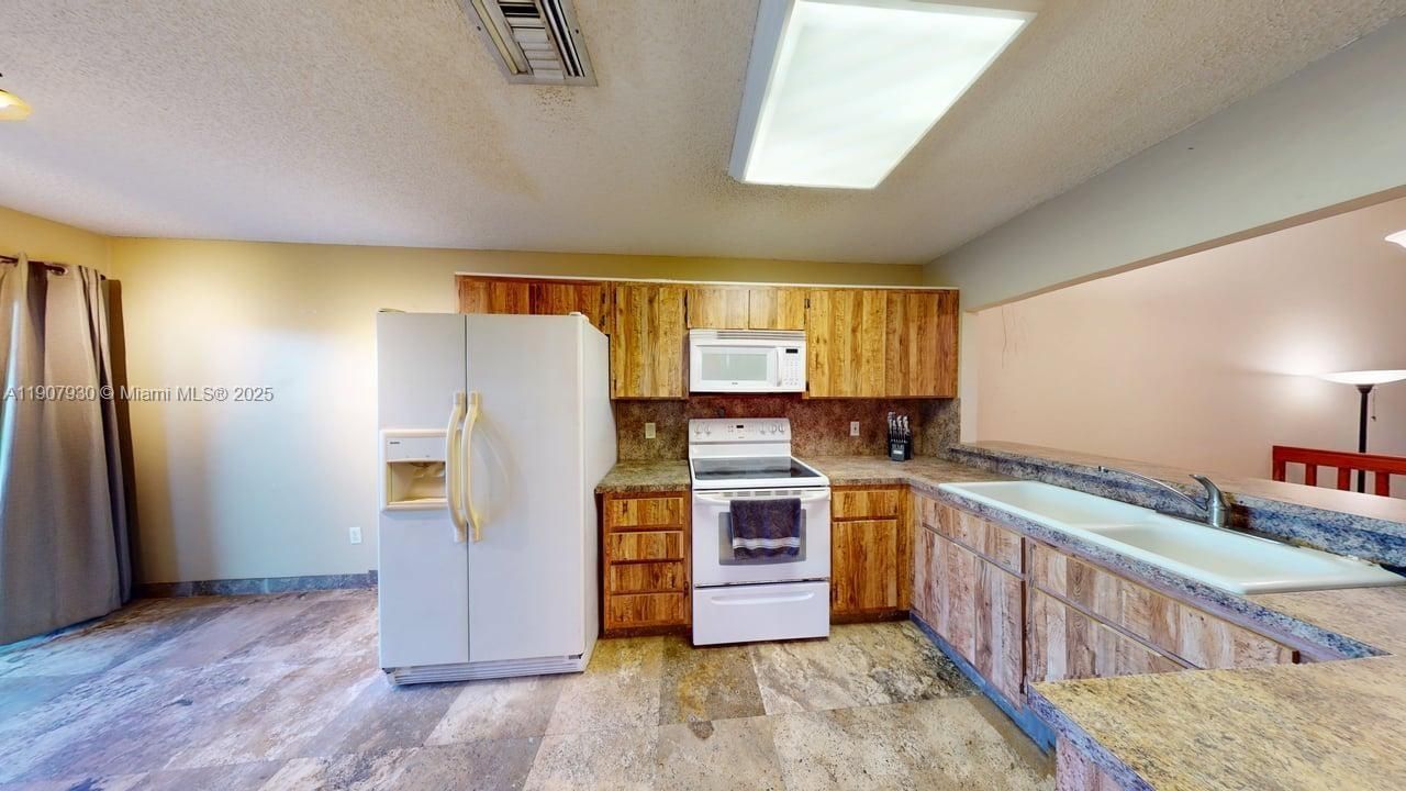 Spacious kitchen featuring rich wood cabinetry, updated appliances, and excellent storage  a perfect blend of functionality and charm.