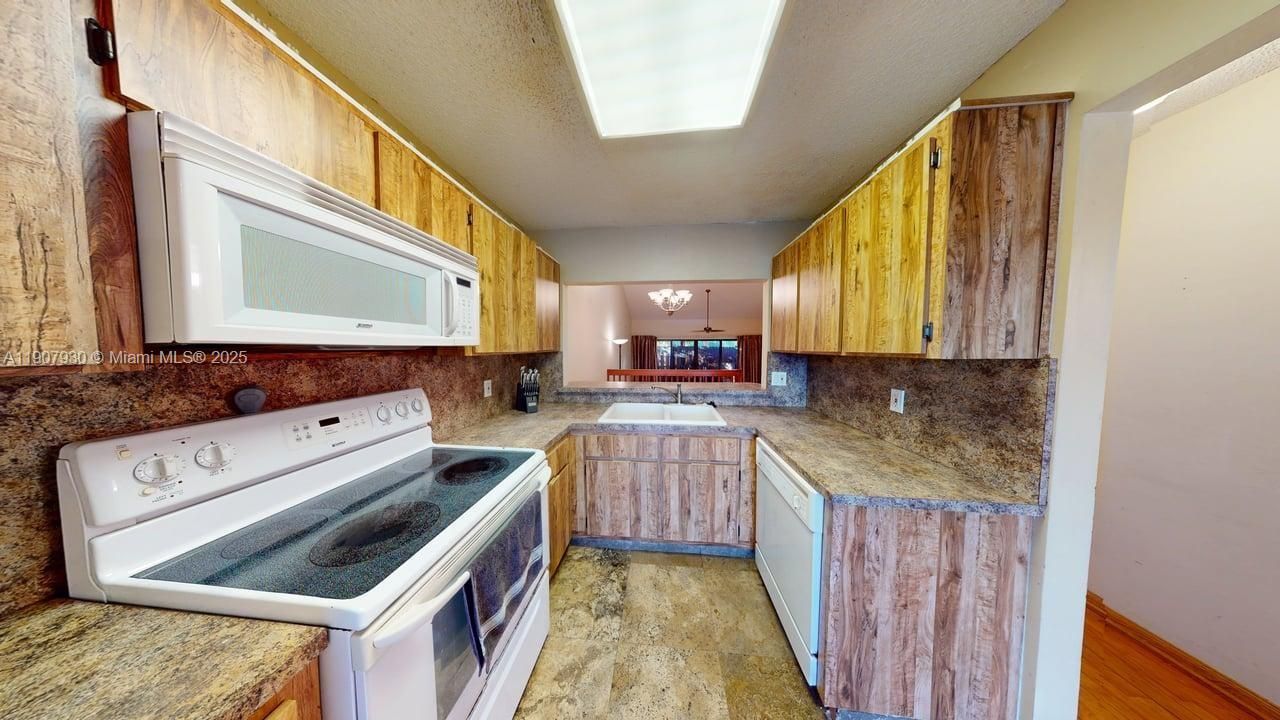 Spacious kitchen featuring rich wood cabinetry, gleaming countertops, and generous prep space — a perfect blend of charm and practicality that opens effortlessly to the dining area.