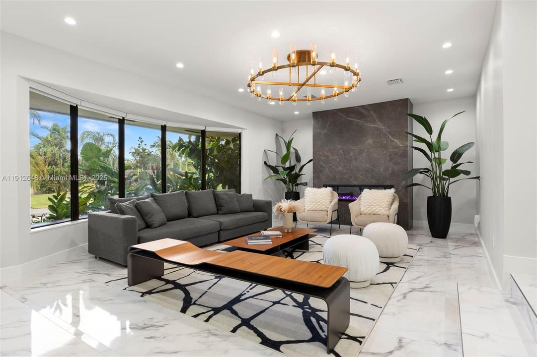 Living Room, with expansive bay window (with motorized blinds) custom tiled fireplace (also heats) with oversized porcelain slabs creating a bold, modern focal point, all with Lumary smart recessed lighting.