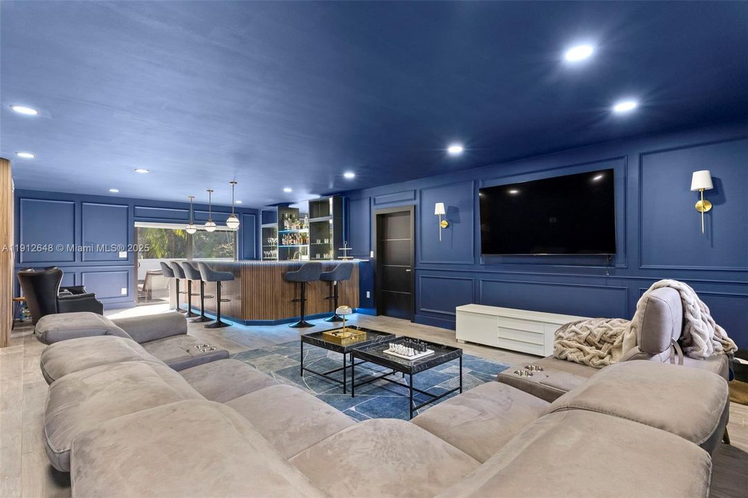 Oversized Entertainment Room/Bar, island designed with custom oak wall painted in blue with custom wall paneling, Lumary smart ambient LED lighting on both bar and ceiling, built in bar area with beverage fridge and ice maker. Walk right out to pool deck. Cabana Bath also located in this lower level lounge.