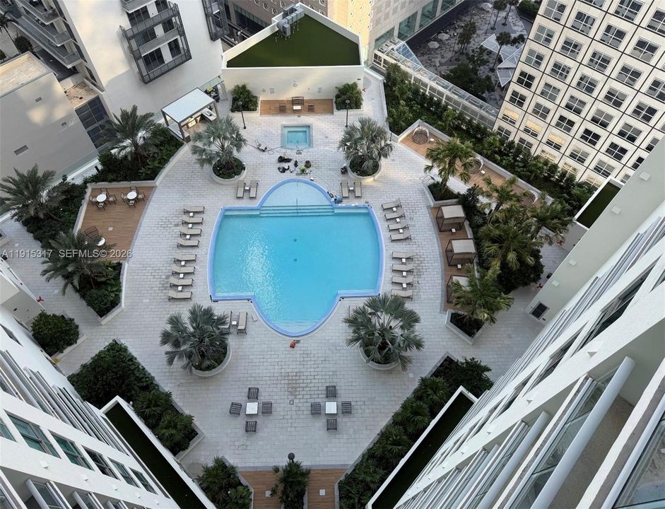 Expansive outdoor amenity deck featuring a swimming pool, integrated spa, and diverse seating areas