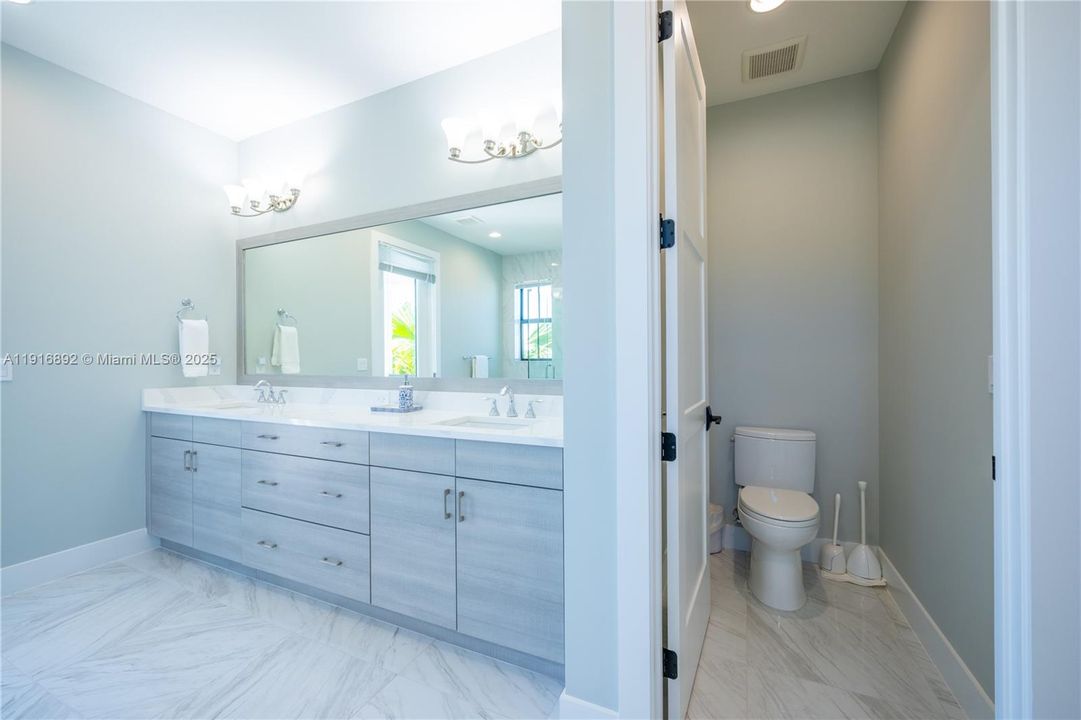 Private water closet alongside a large his and hers vanity