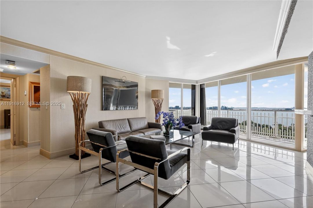 A bright, spacious living area showcasing sweeping panoramic views of the sparkling water and the iconic Miami skyline