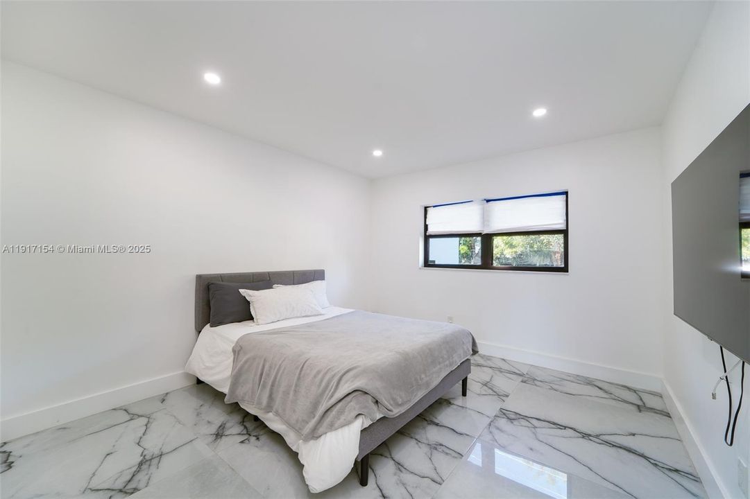 Generous bedroom with large window, polished flooring, and space for a full bedroom setup.