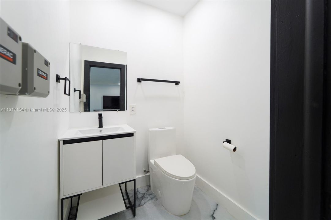 Modern half bath with sleek vanity, black hardware, and contemporary finishes.