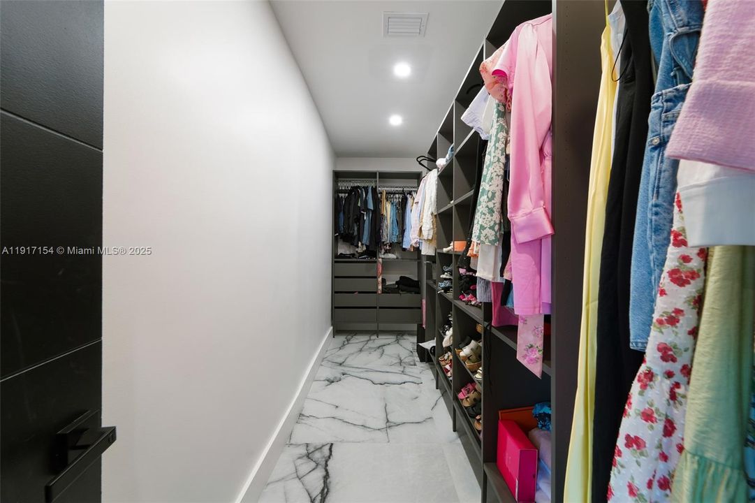 Large custom walk-in closet with built-in shelving, drawers, and organized storage throughout.