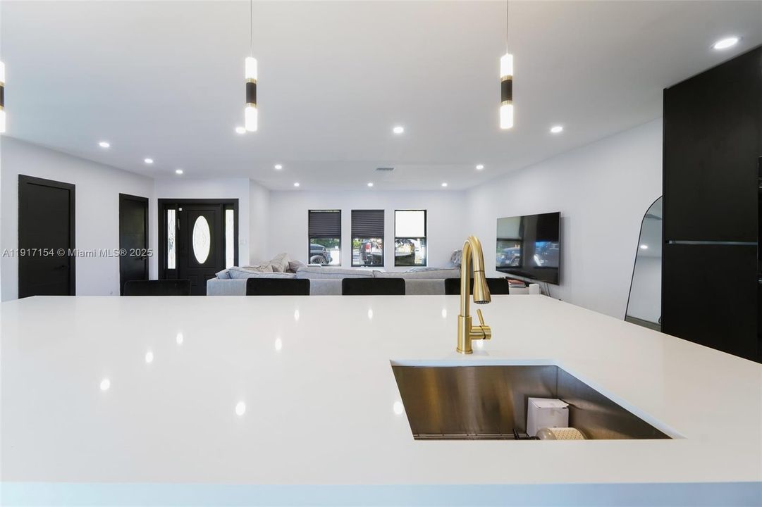 Expansive waterfall island overlooking open living space with LED lighting throughout.