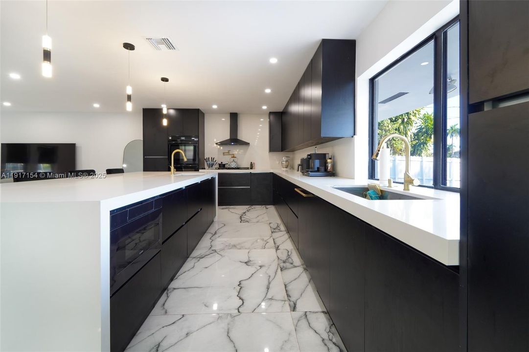 Open-concept kitchen with large entertainment island and elegant gold fixtures.
