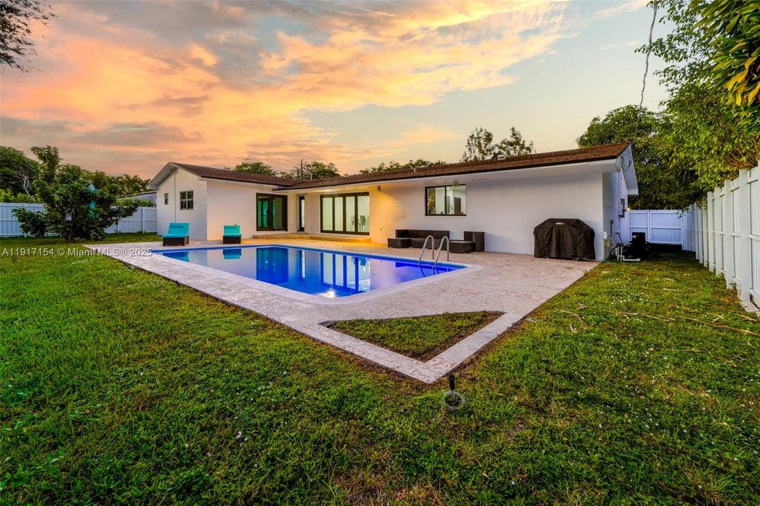 Spacious fenced backyard with resurfaced pool, patio seating, and multiple access points to the home.