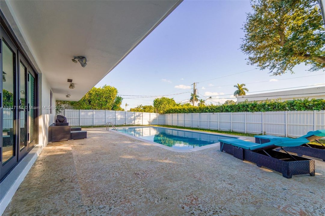 Spacious covered patio overlooking the resurfaced pool and fenced yard. Ideal for outdoor living.