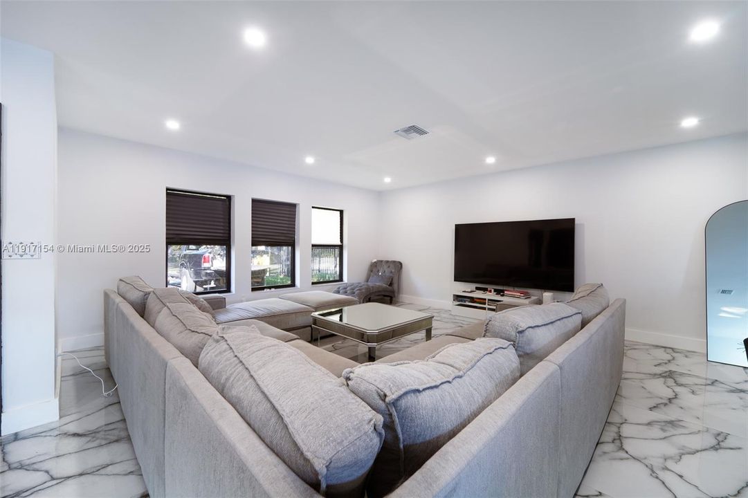 Large living room with recessed lighting and space for oversized seating and media setup.