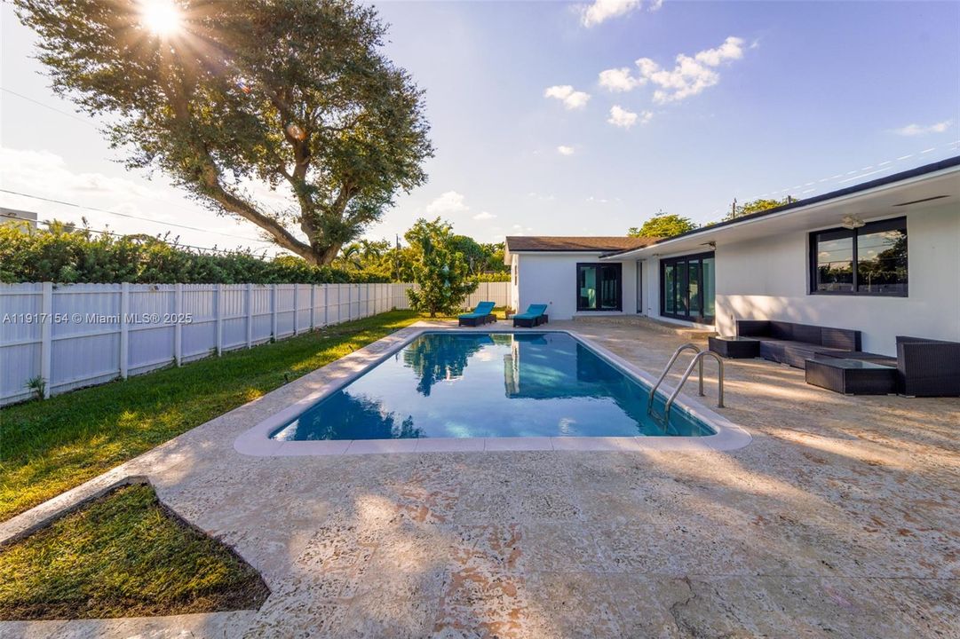 Large backyard with resurfaced pool, sun loungers, and spacious patio for entertaining.