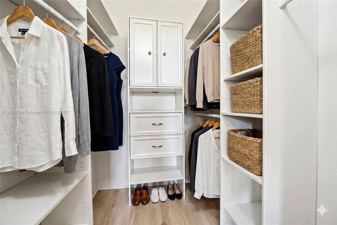 Spacious walk-in closet with custom shelving — virtually decluttered to showcase storage potential.