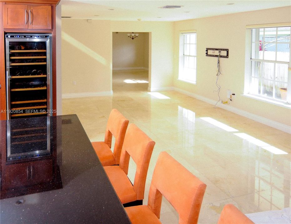 View of the wine refrigerator, and of the living room, and dining room in the distance.