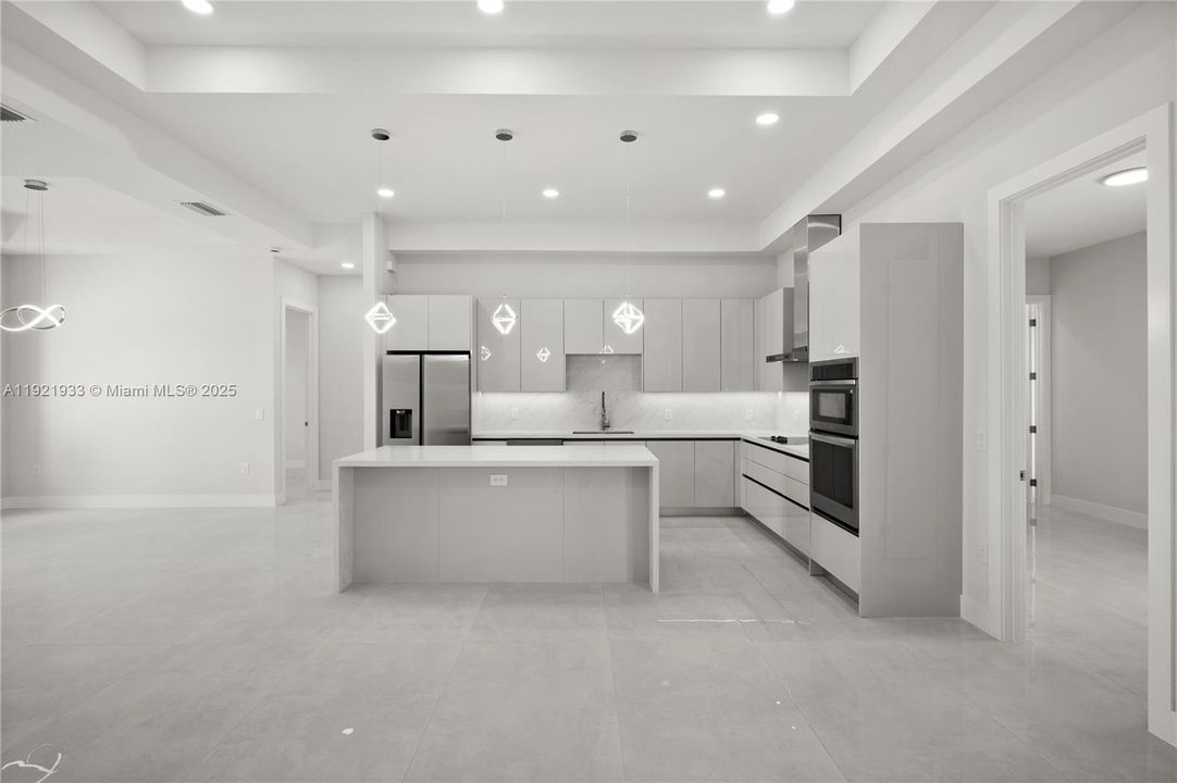 Kitchen featuring modern cabinets, hanginglight fixtures, a center island, backsplash, andstainless steel appliances