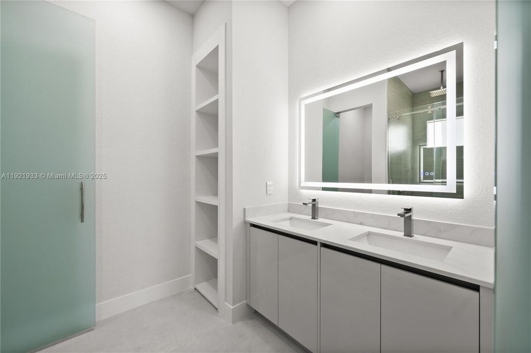 Bathroom with double vanity, a shower stall,and a closet