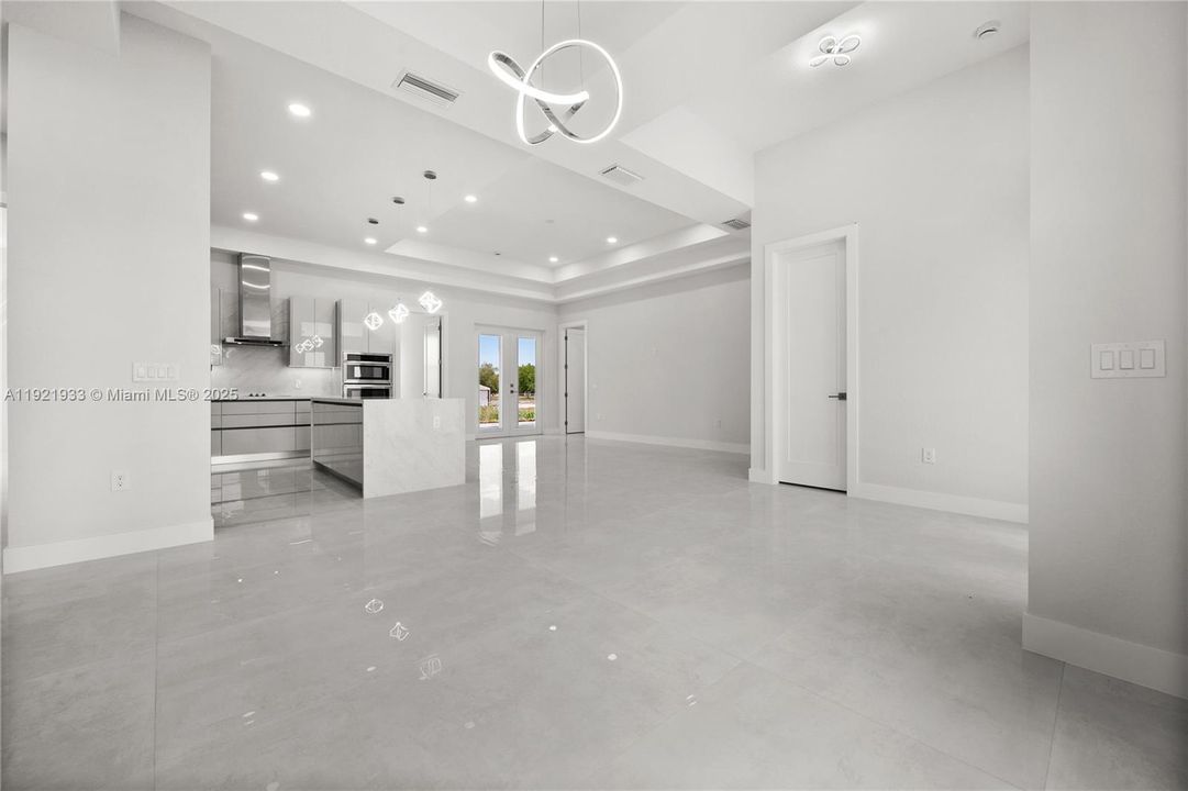 Unfurnished living room with a raised ceiling,french doors, and recessed lighting