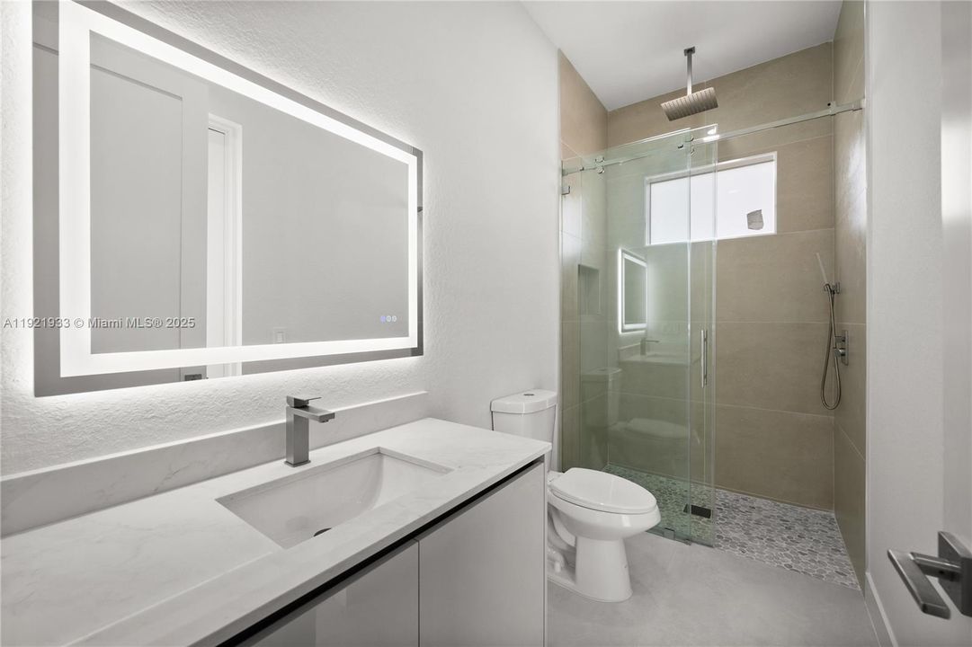 Bathroom featuring vanity, a stall shower, anda textured wall