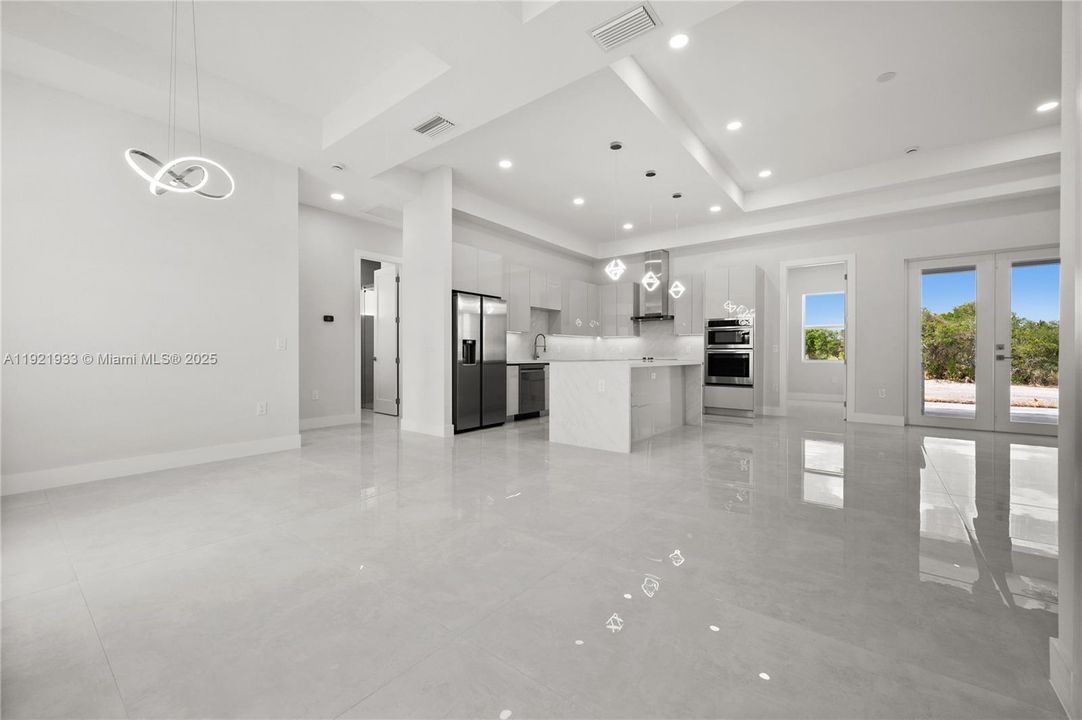 Kitchen with open floor plan, a raised ceiling,decorative light fixtures, stainless steelappliances, and white cabinets