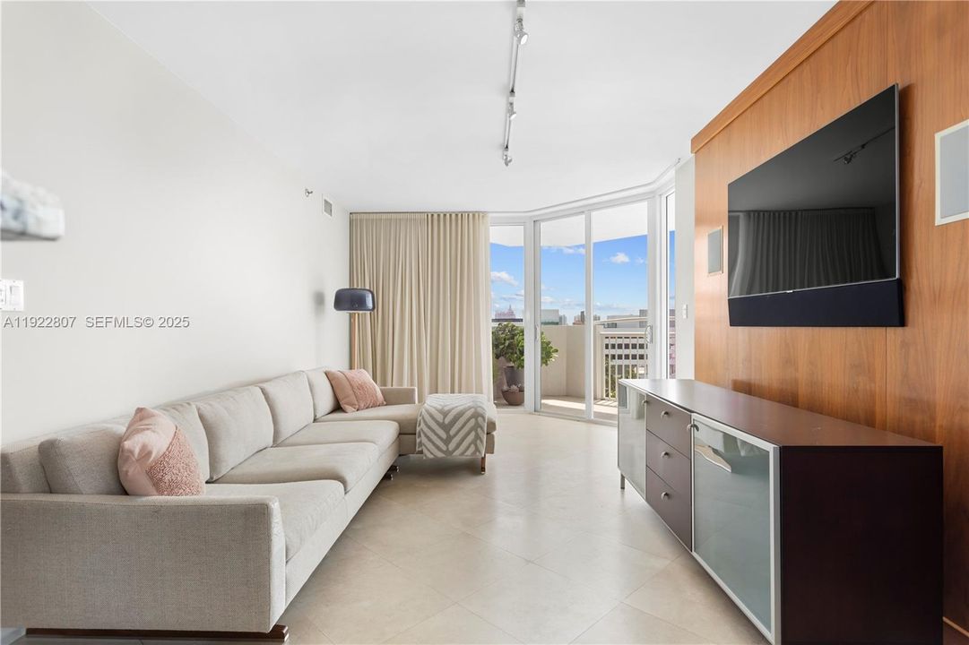 Bright and modern living room featuring floor-to-ceiling windows, abundant natural light, and an open layout—perfect for relaxing or entertaining. Sleek finishes and city-view backdrop add to the contemporary feel.