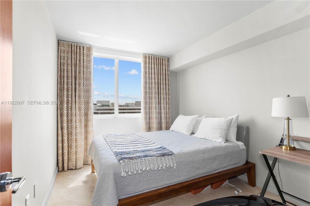 Spacious bedroom featuring a minimalist design, neutral tones, and oversized windows for excellent natural lighting.