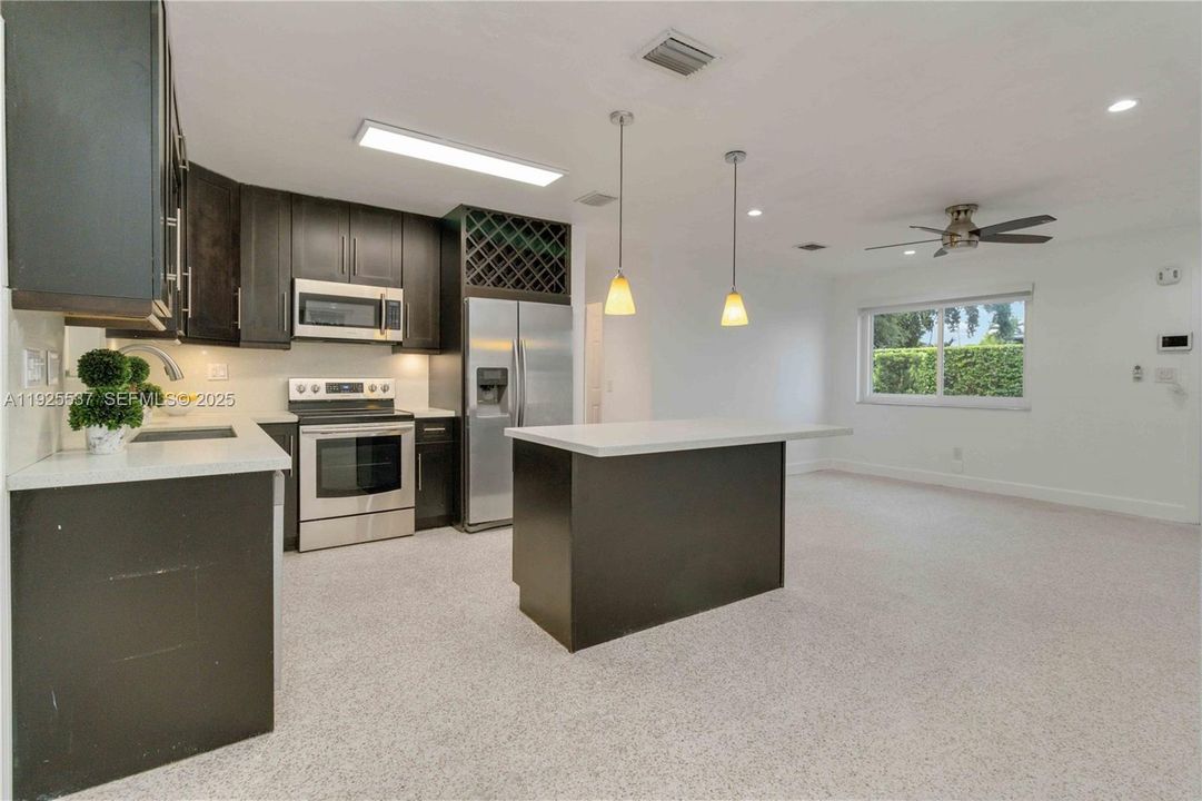 Spacious and remodeled kitchen offers large island, quartz counter tops, elegant wood cabinets with ample storage, and stainless-steel appliance