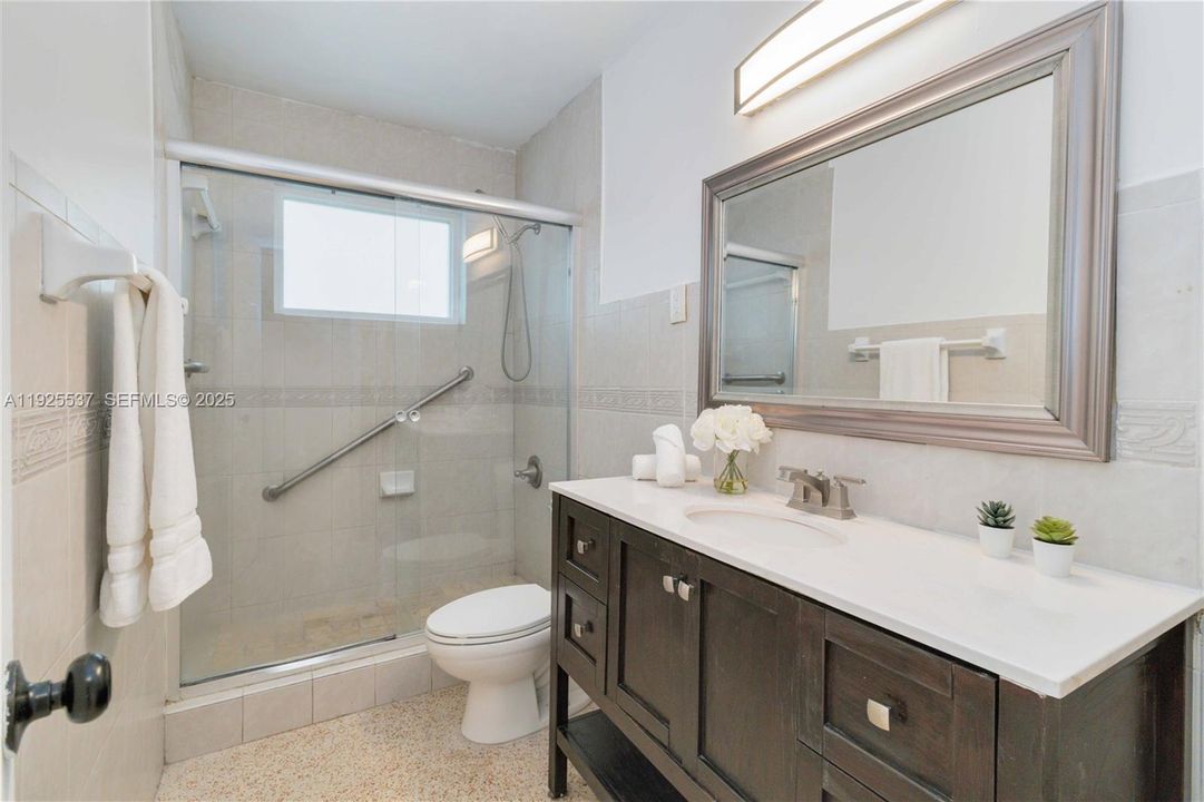 Remodeled and spacious bathroom with large shower, plenty of natural light and roomy vanity