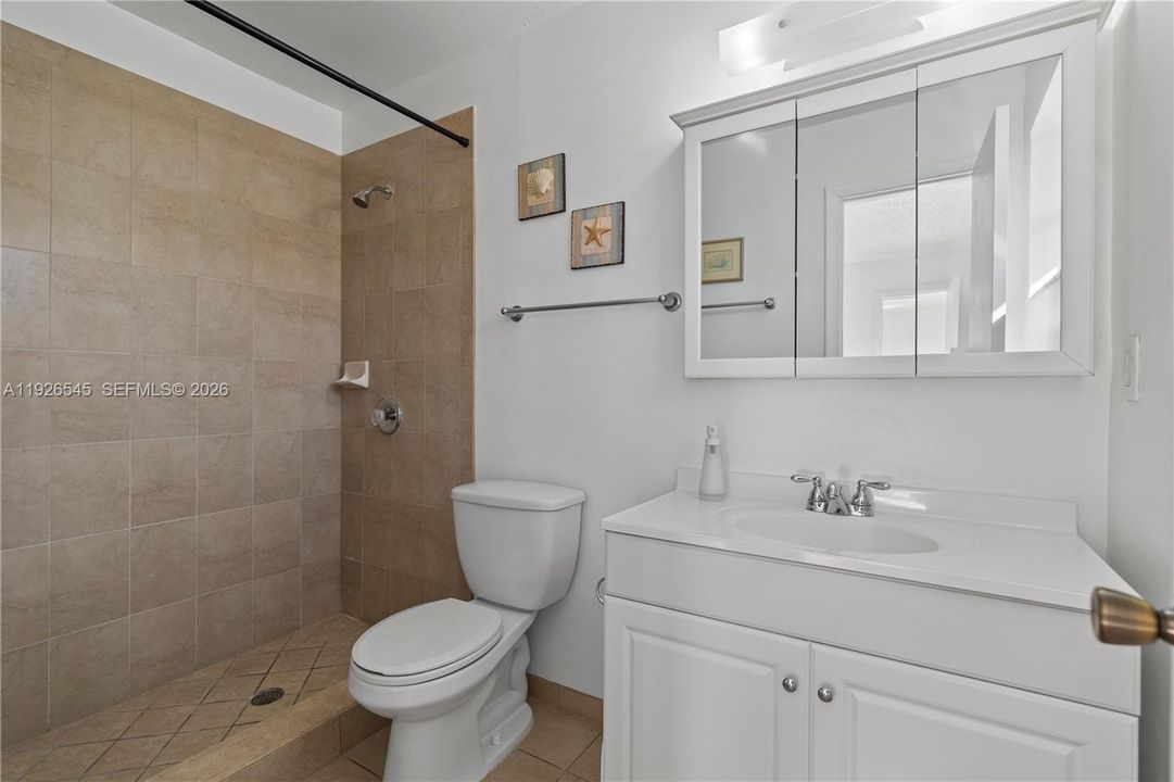 Primary bathroom with a shower, beautiful tile finishes, and a window for natural light.