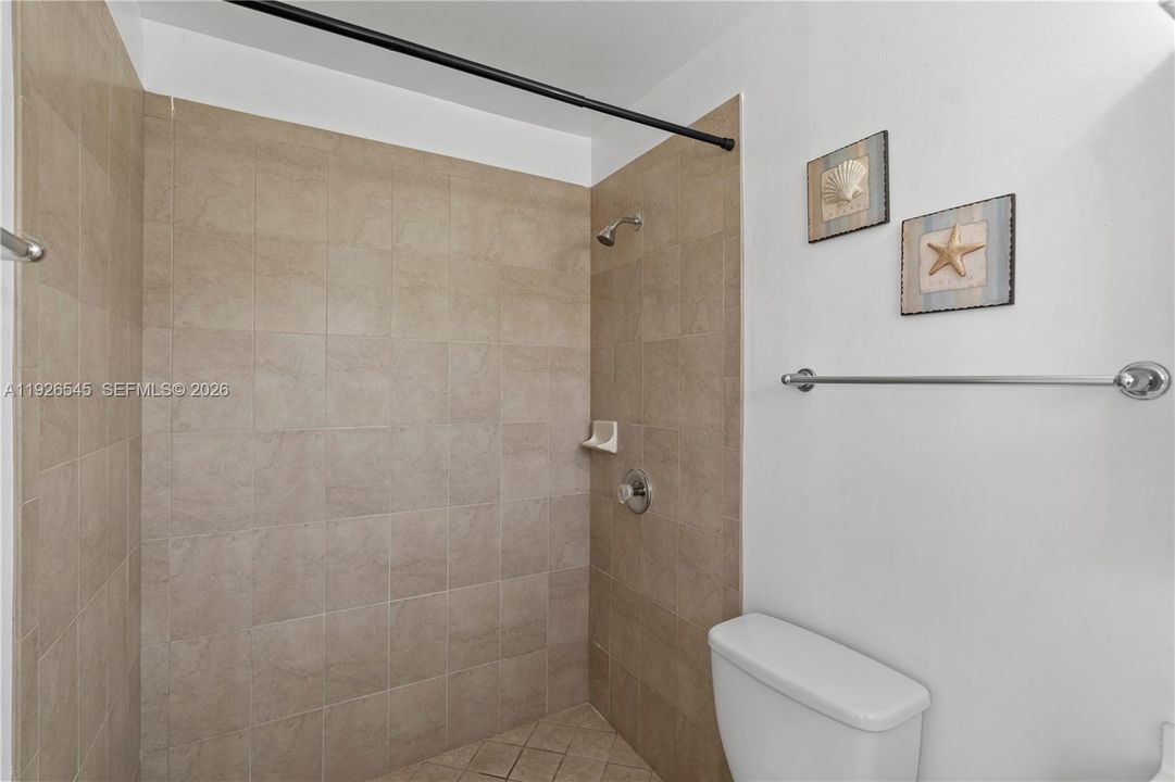 Primary bathroom with a shower, beautiful tile finishes, and a window for natural light.