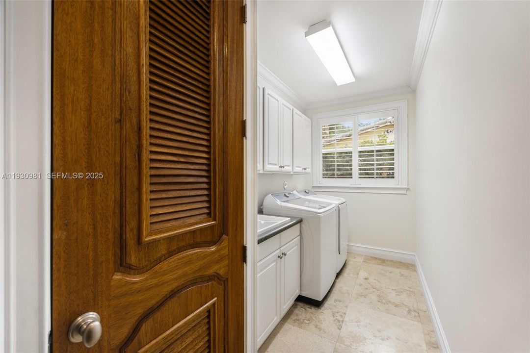 Laundry room with built-in cabinetry and connecting to double car garage