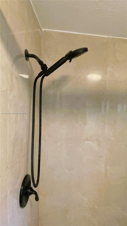 Walk-in shower features modern floor-to-ceiling tile, a rainfall-style showerhead, and sliding glass doors