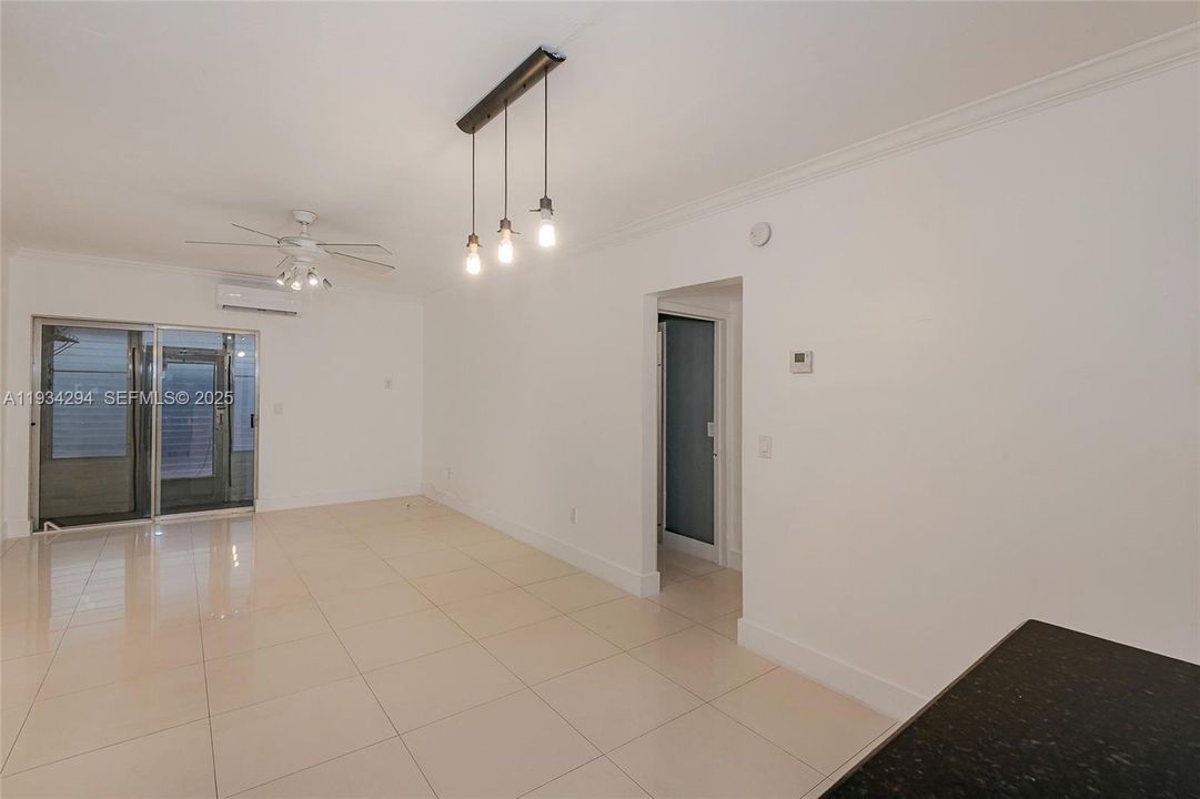 The view from the end of the kitchen to the dining/living room area with the doorway into the bedrooms and bathrooms. The sliding doors lead to the rear porch with windows to the outside rear yard and patio. Above the sliding door is the mini-split air conditioning unit for this room.