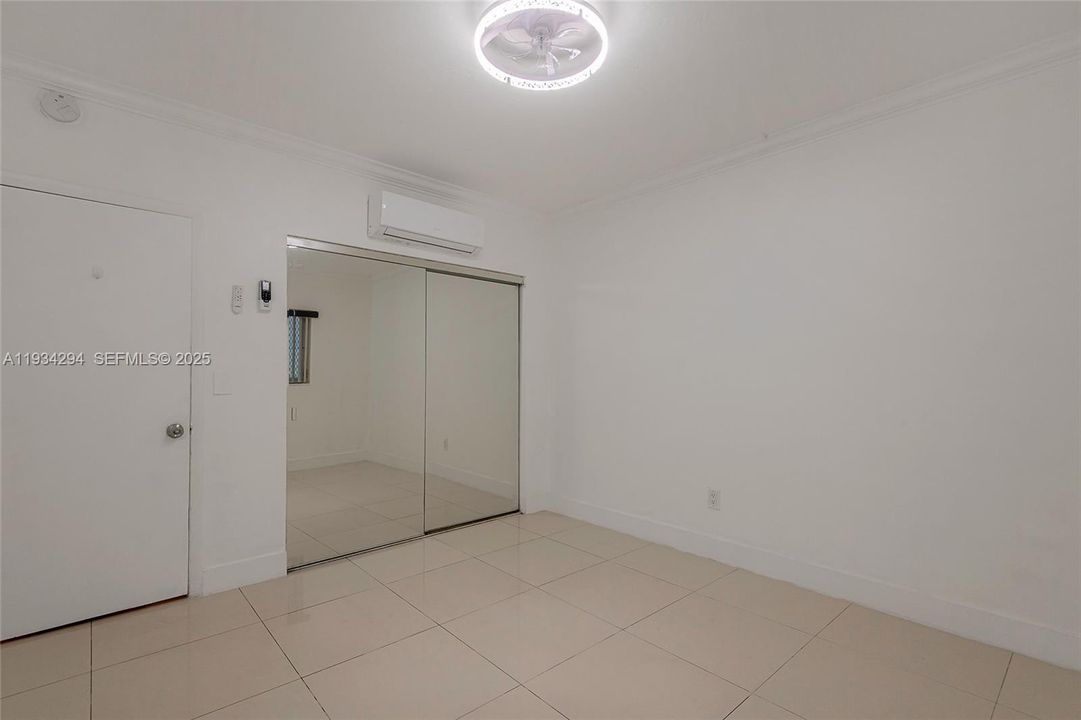 This is the front bedroom inside the unit. Above the mirrored closet doors is the mini-split unit for this room. The door on the left is the bedroom entrance.