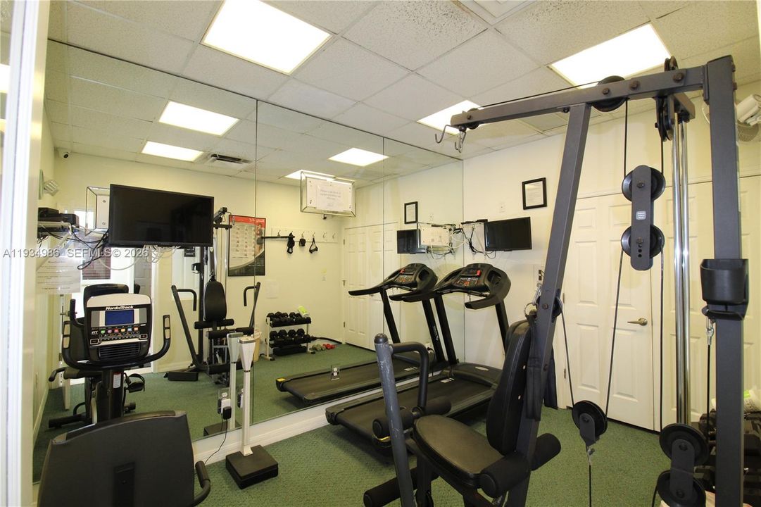 Full-wall mirrored accent, drop ceiling with recessed lighting, and wall-mounted door hardware