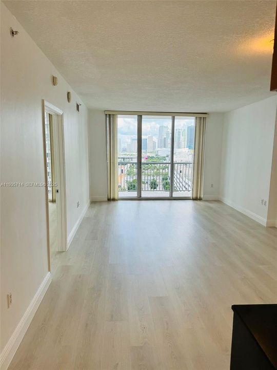 Spacious living area with laminate floors and access to balcony.