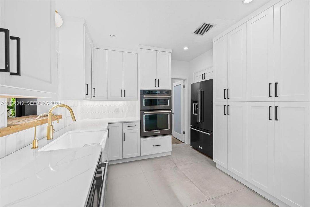 Custom kitchen featuring farmhouse sink, imperial grey appliances, matte black hardware and brushed gold fixtures.