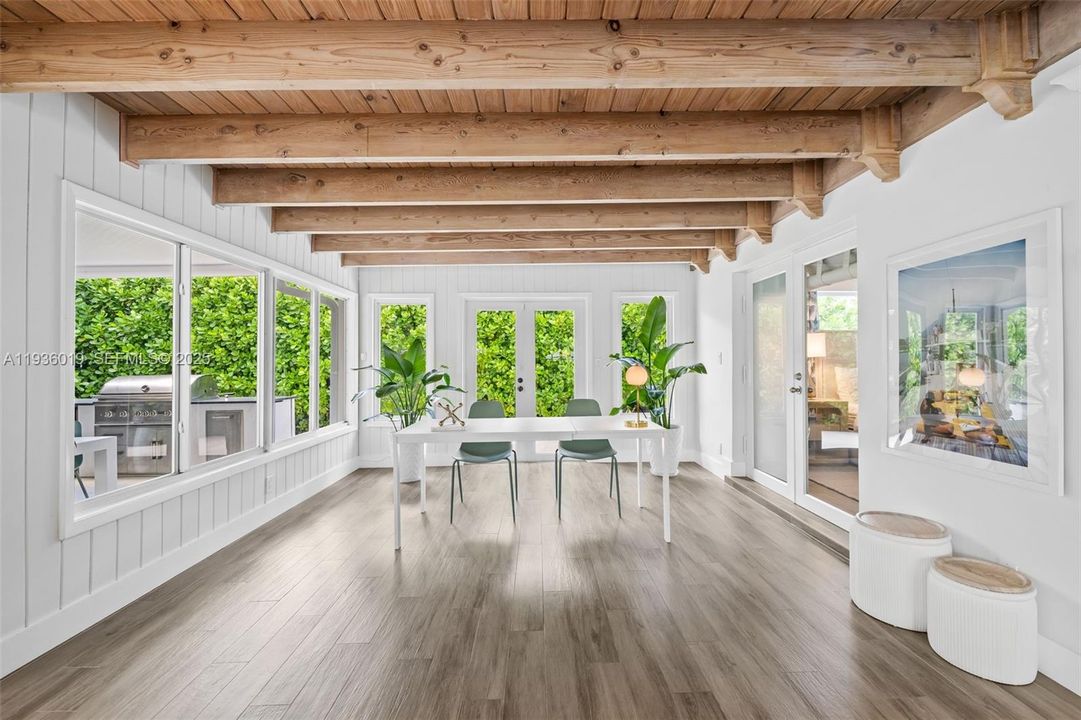 View from formal dining to family room featuring wooden beams. Impact doors leading to summer kitchen and pool.